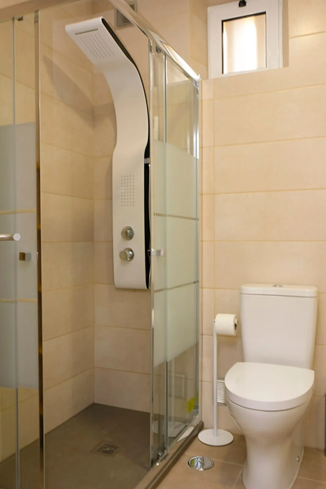Un baño alicatado con una ducha de vidrio y un inodoro.