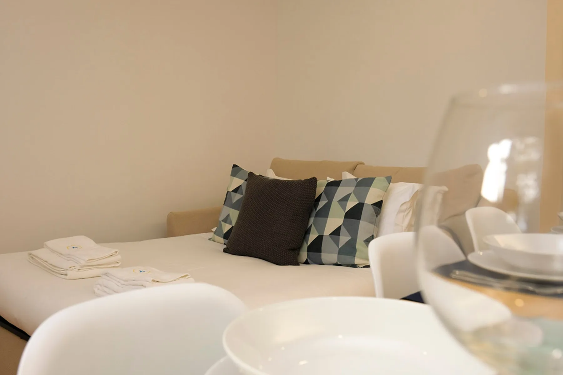 Una mesa de comedor está junto a una zona de asientos con cojines estampados.