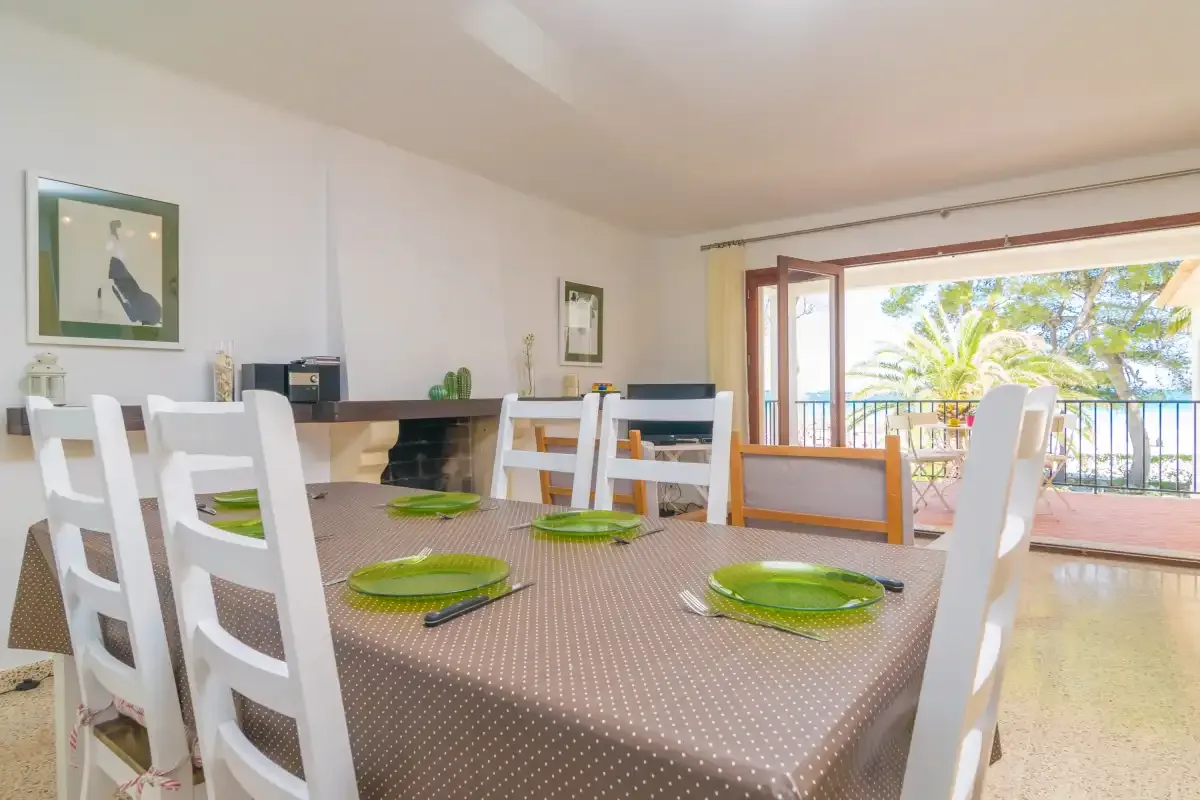 A dining area with a table and chairs beside open doors to a balcony.