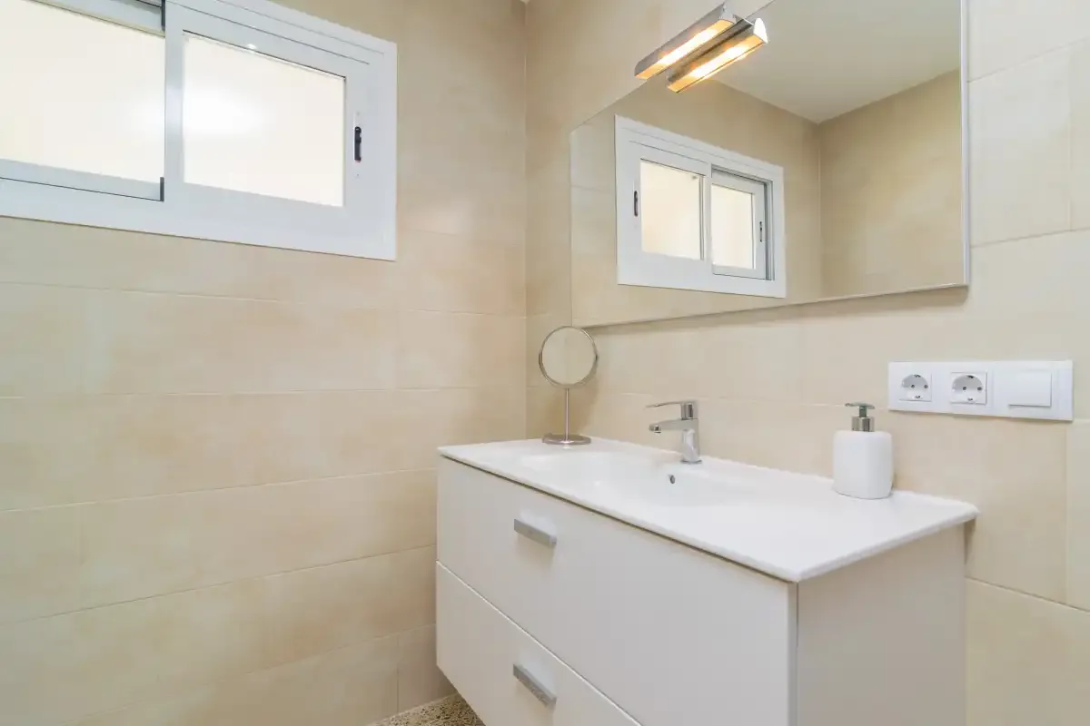 A bathroom vanity with a sink and a large wall mirror.