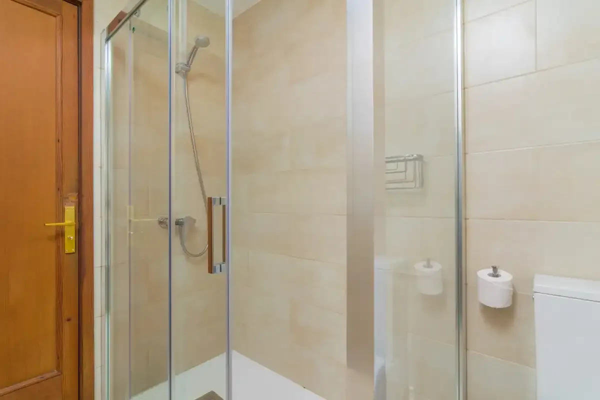 A tiled bathroom with a glass shower and wall-mounted fixtures.