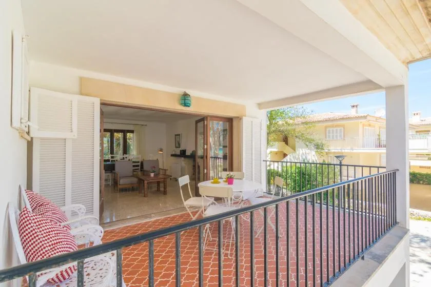 Una terraza cubierta con asientos y una mesa de comedor da a edificios vecinos.