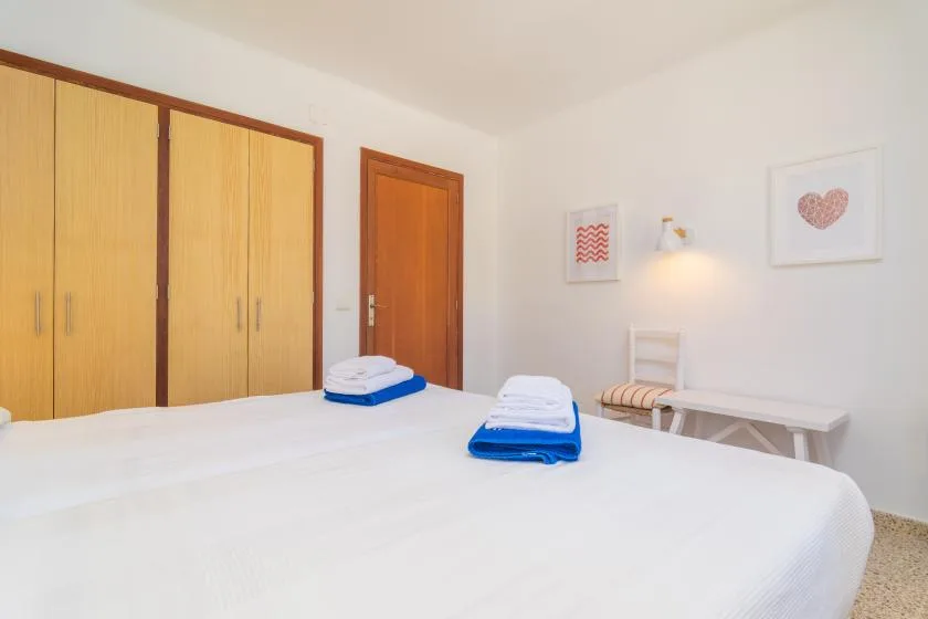 A bright bedroom with a neatly made bed and wooden wardrobes.