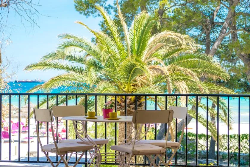 A balcony dining area overlooks palm trees and the sea.