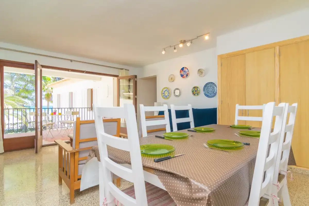 A dining area with a table set with green plates beside open balcony doors.