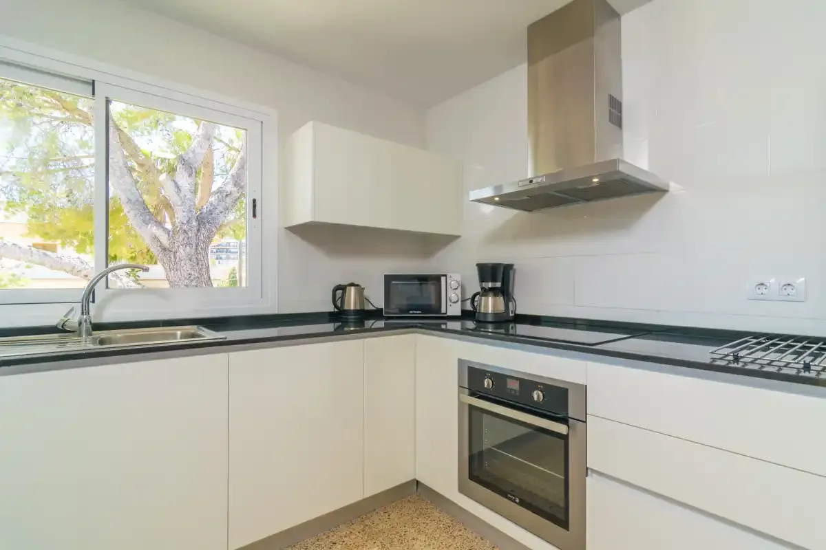 A bright kitchen with light-colored cabinets, a window, and countertop appliances.