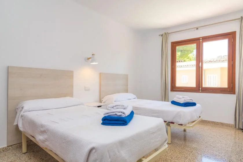 A bright bedroom with two beds and folded towels.
