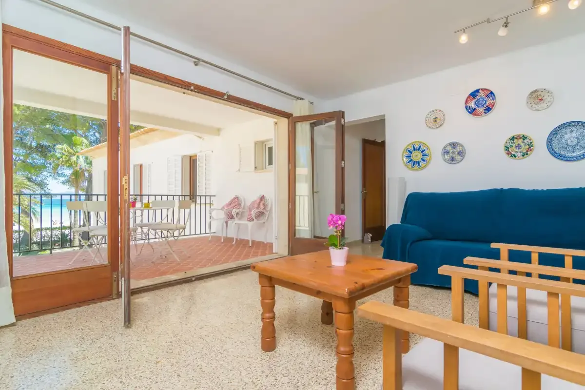 A living room with blue seating and a wooden coffee table beside an open balcony.