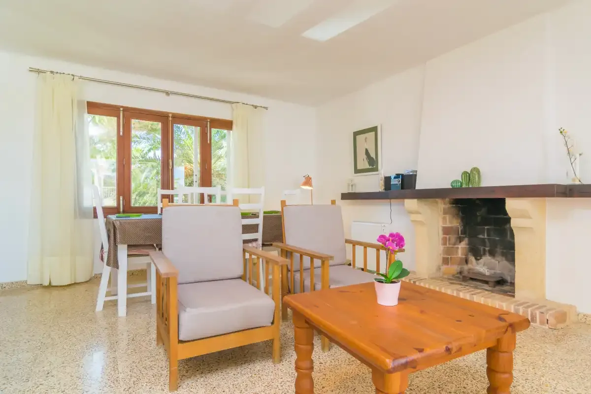 A bright living room with seating, a wooden coffee table, and a fireplace.