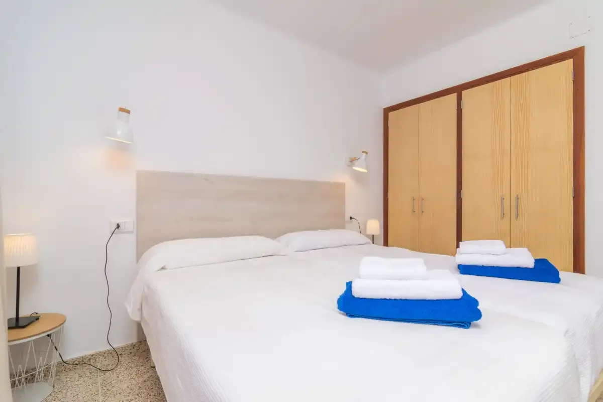 A bedroom with a double bed and folded towels on the bed.