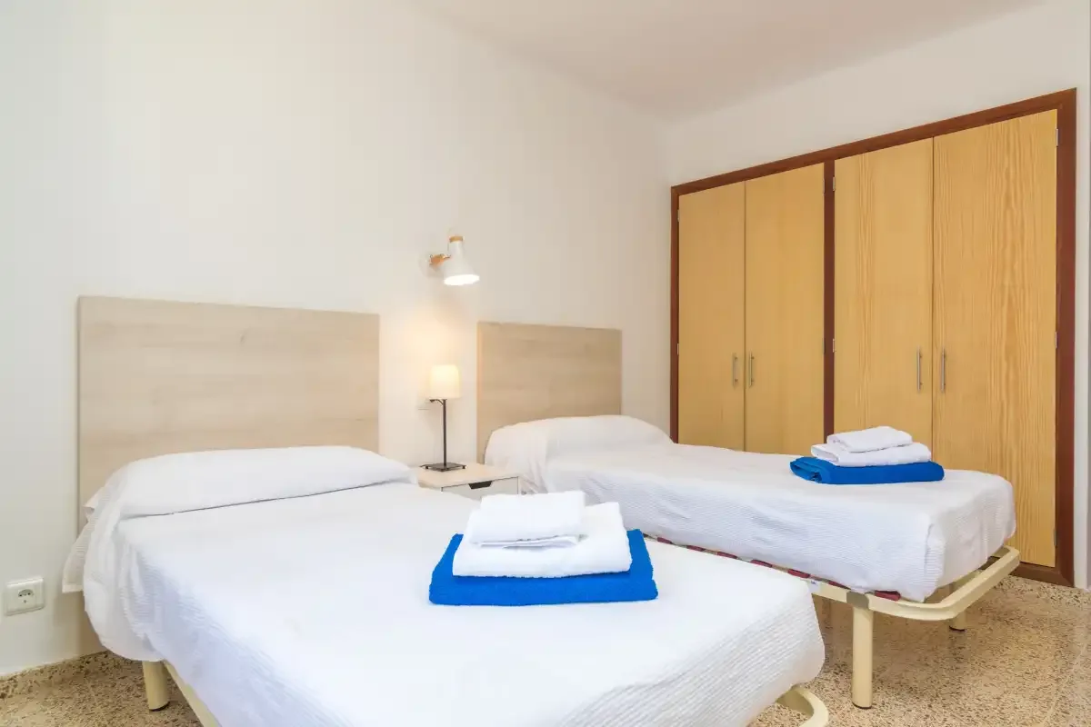 A bedroom with two beds and wooden wardrobes.