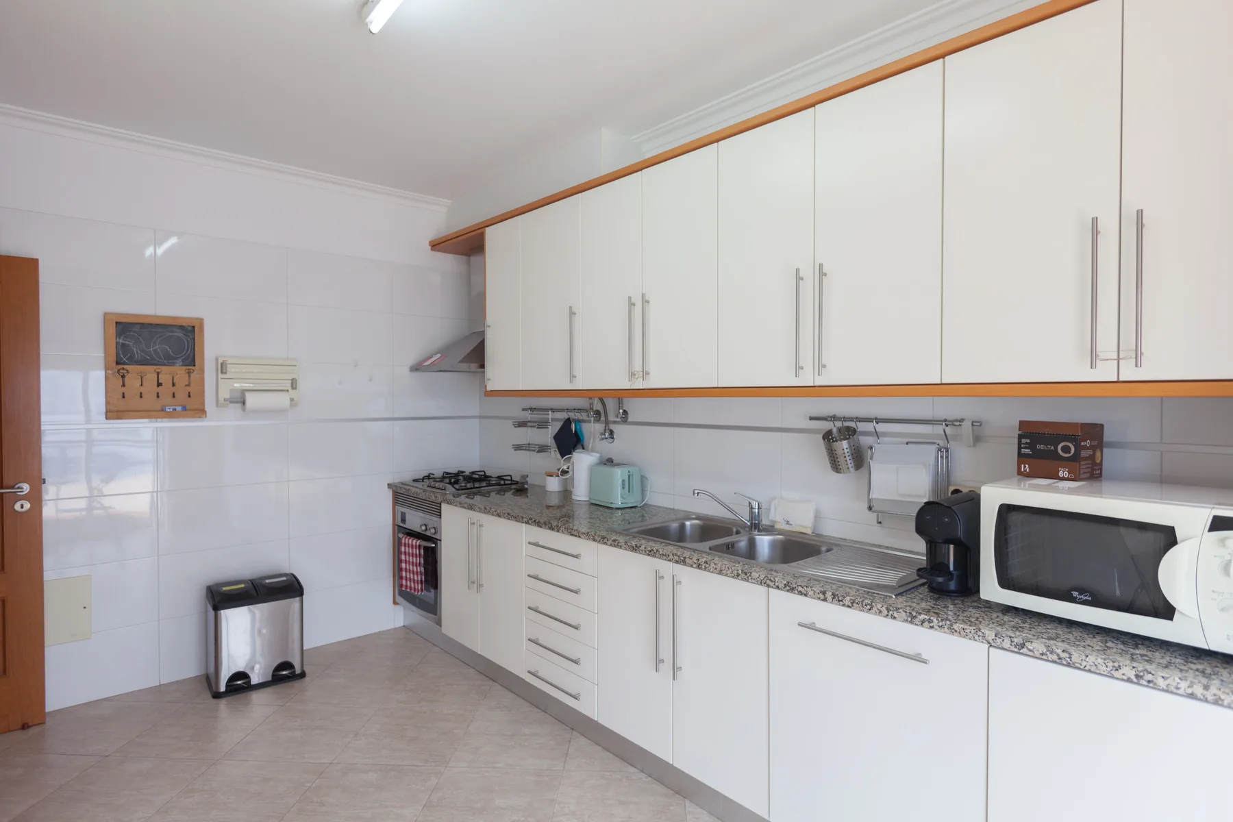 A bright kitchen with white cabinets, a countertop, and a microwave.