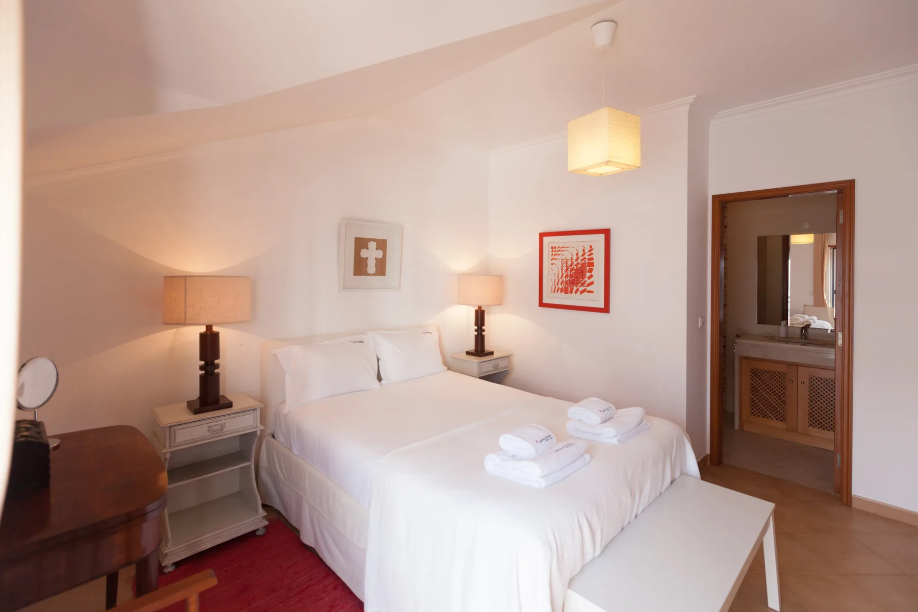 A bright bedroom with a neatly made bed and matching bedside lamps.