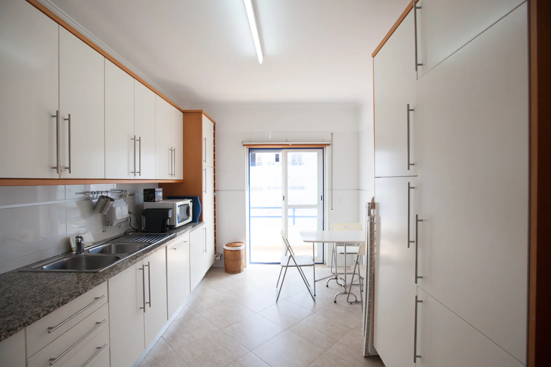 A bright kitchen with cabinets, a counter, and a small dining table by the window.