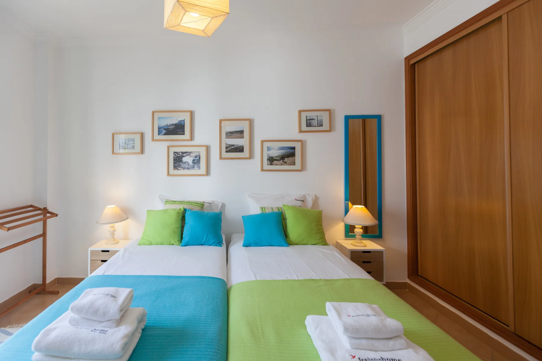 A bedroom with two beds dressed in turquoise and green bedding.
