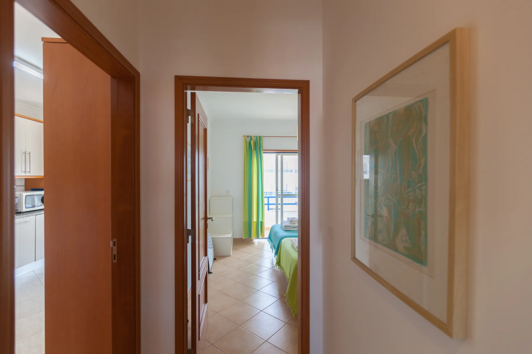 A hallway opens toward a bedroom with a bright window and colorful curtains.