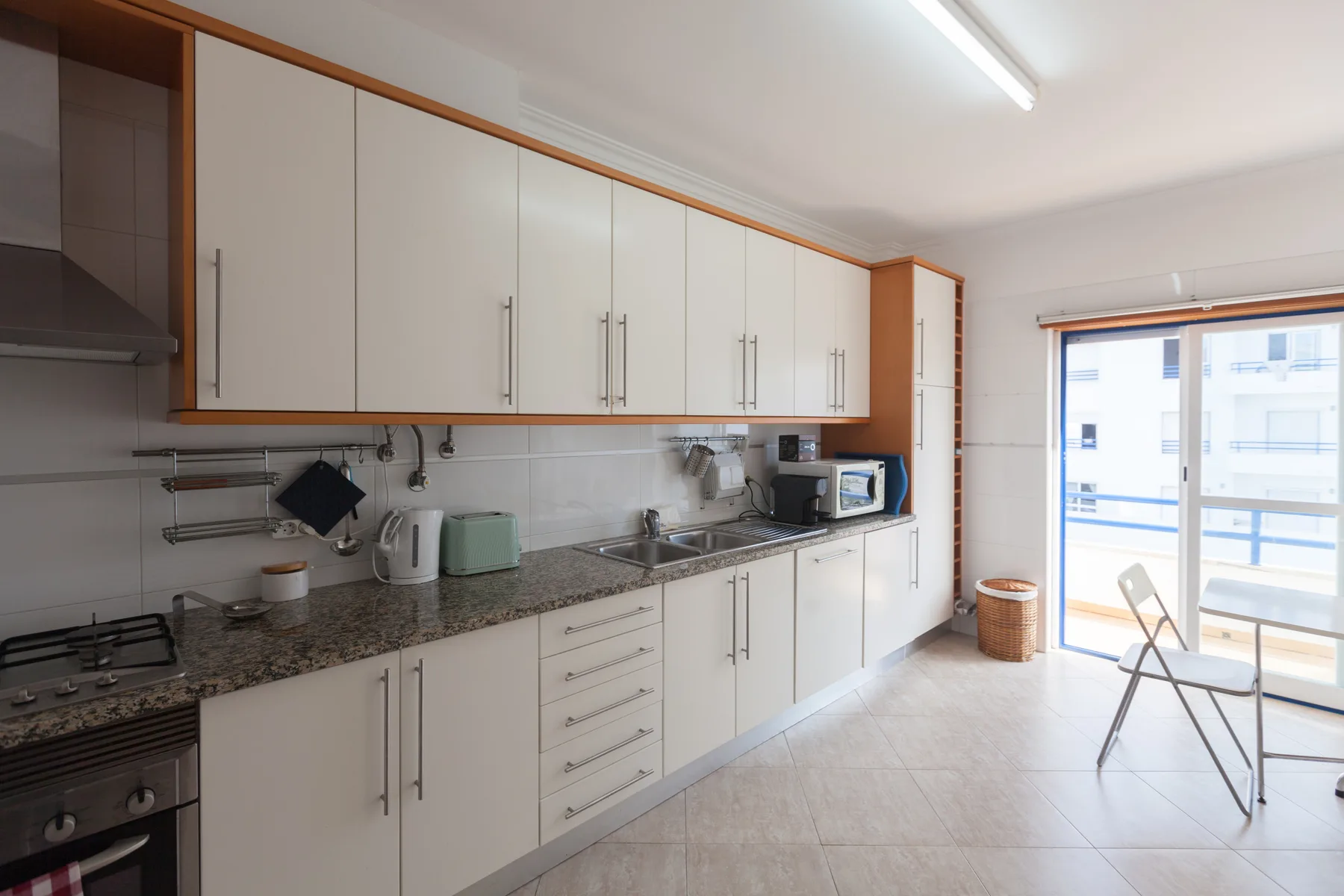 A bright kitchen with white cabinets and a long countertop.