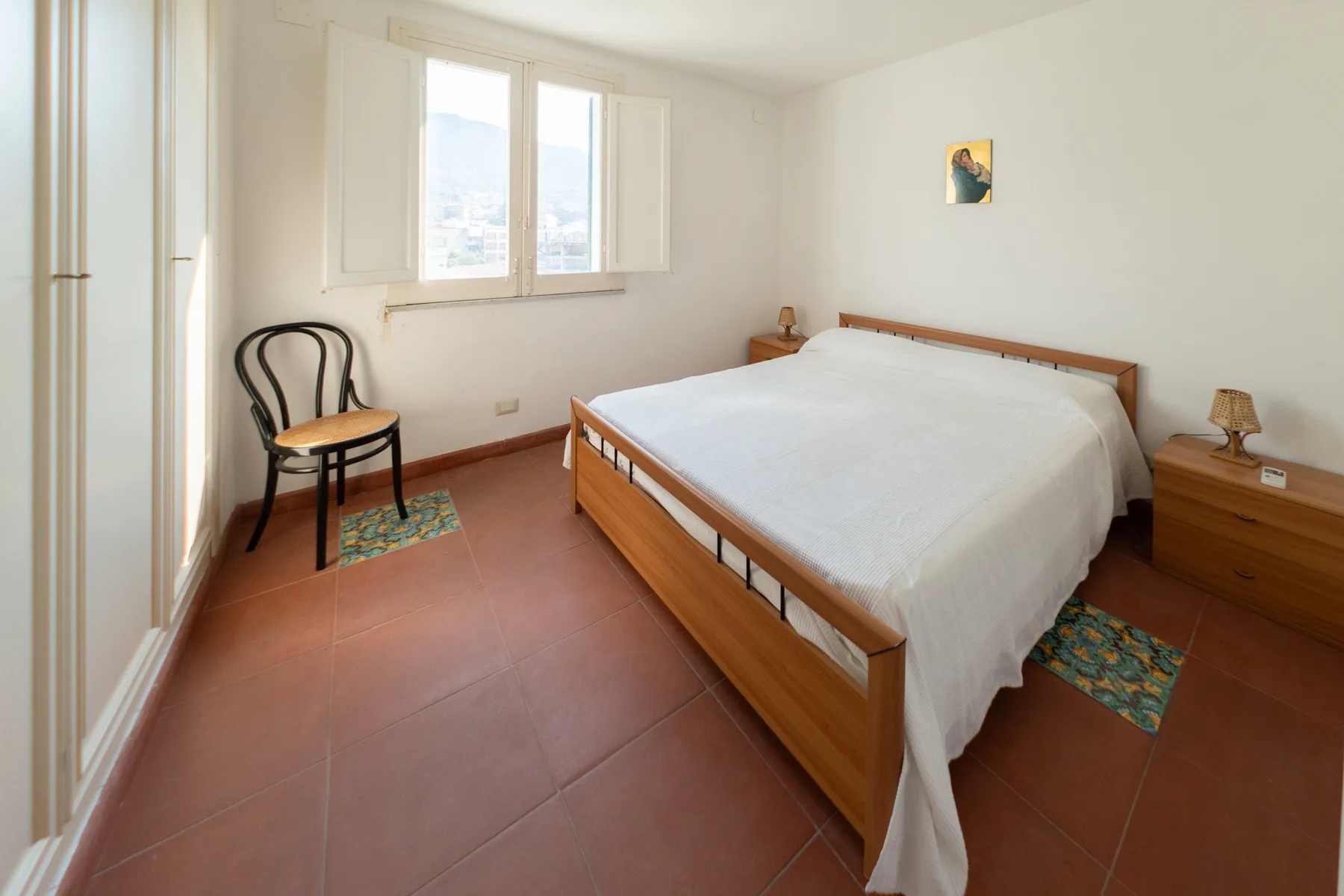 Un dormitorio con una cama de madera, una silla y una ventana.