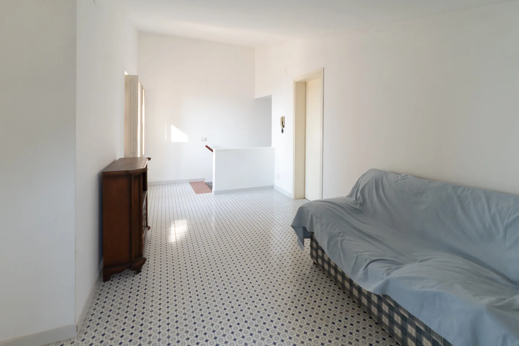 Una habitación luminosa con una zona para sentarse cubierta y suelo de baldosas estampadas.