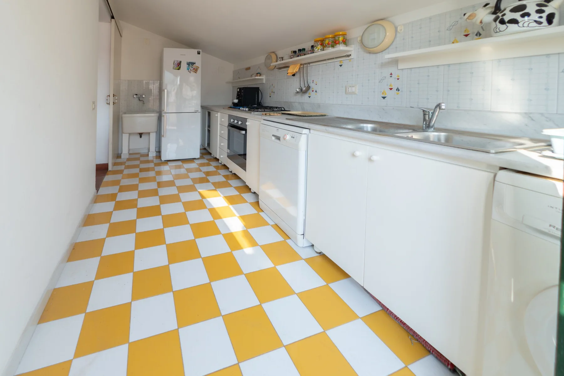 A bright kitchen with white cabinets and a yellow-and-white checkered floor.
