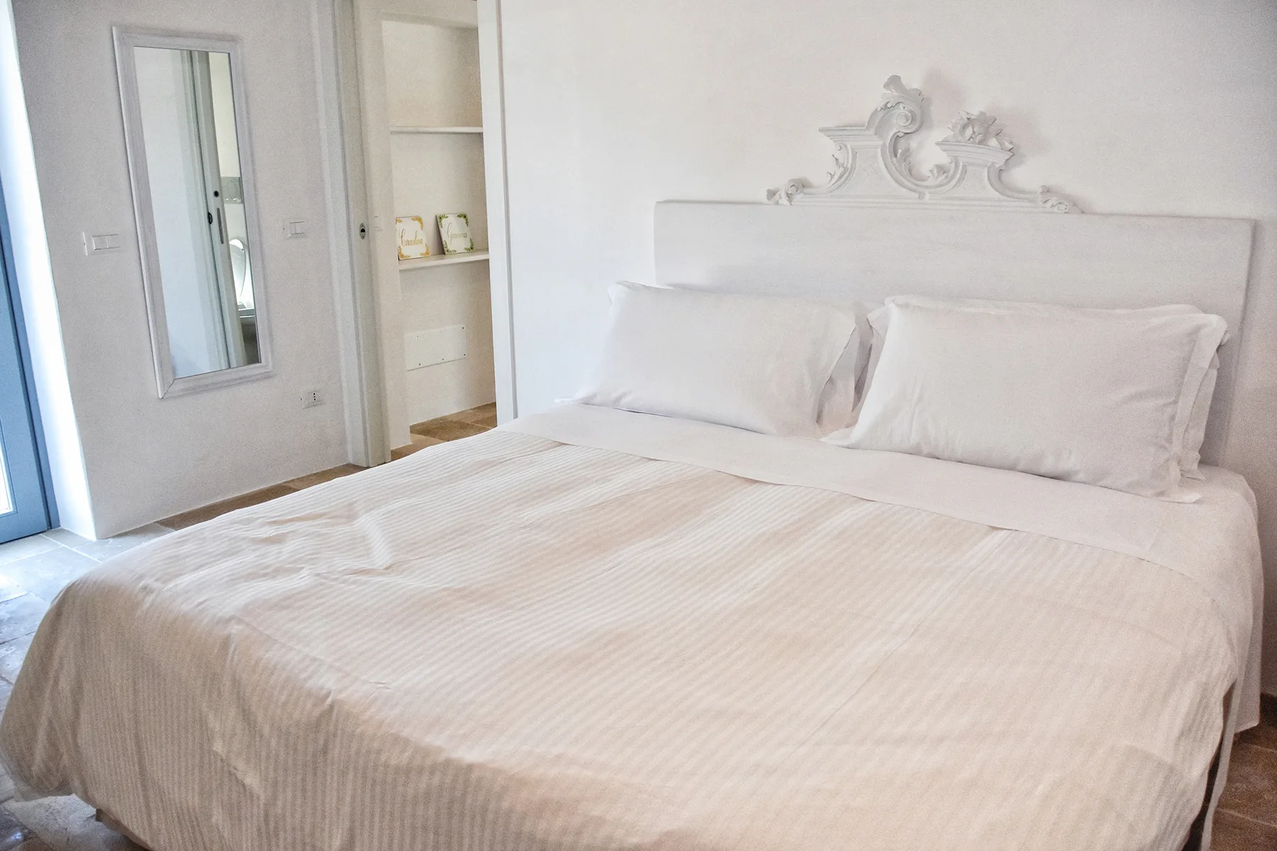 Un dormitorio con una cama bien hecha y un cabecero blanco decorativo.