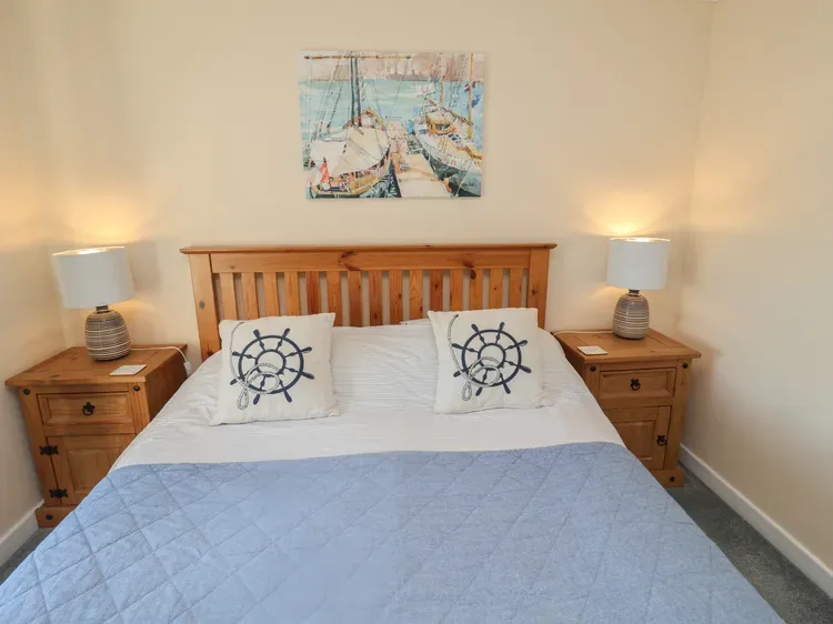 Un dormitorio con una cama tendida y mesitas de noche a juego.