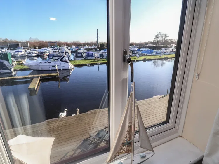 Una ventana da a una marina, con un velero en miniatura sobre el alféizar.