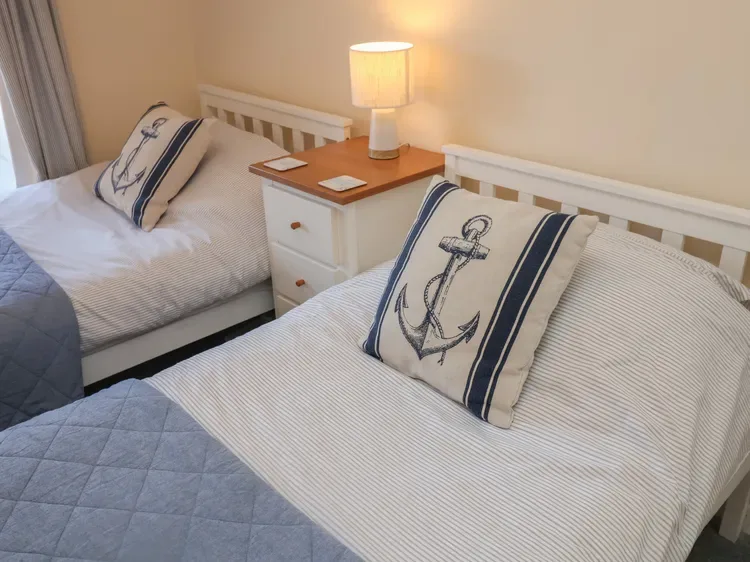 Un dormitorio con dos camas y una lámpara encendida sobre la mesita de noche.