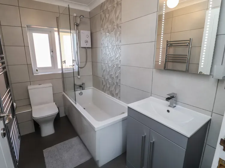 Un baño con azulejos, bañera, ducha, inodoro y lavabo.