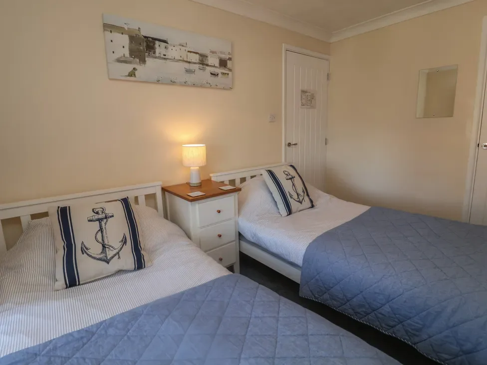 Un dormitorio con dos camas individuales, ropa de cama azul y una lámpara encendida.