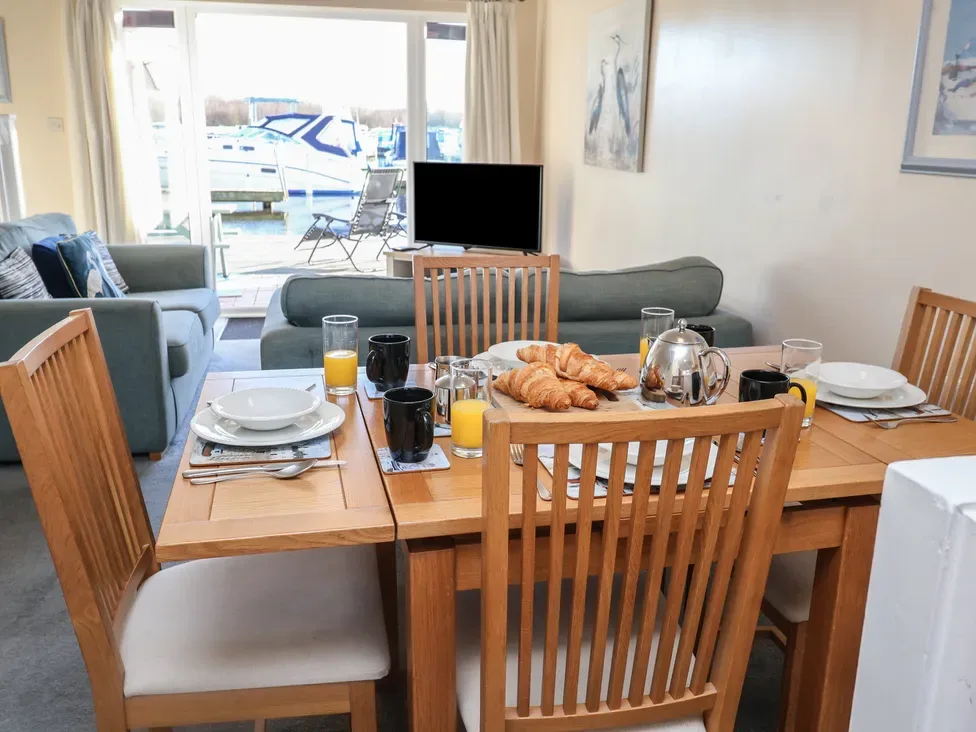 Comedor con la mesa puesta y una sala de estar visible al fondo.