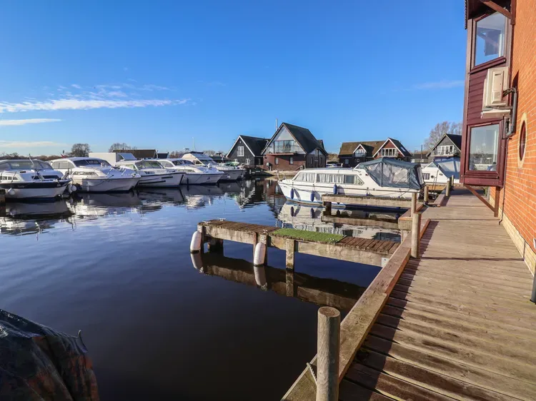 Un puerto deportivo con barcos amarrados junto a una pasarela de madera en un día despejado.