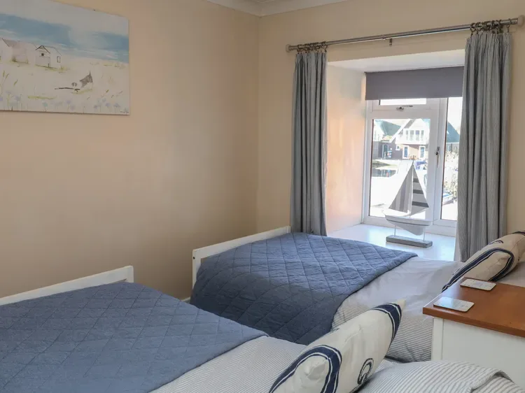 Un dormitorio con dos camas junto a una ventana grande con cortinas.