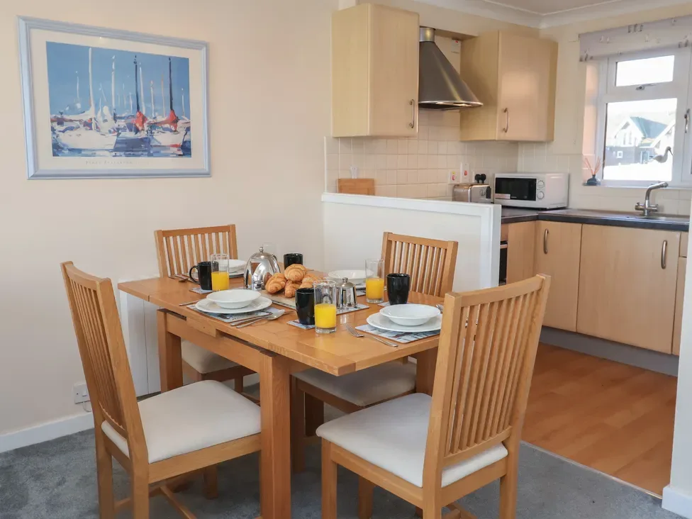 Comedor con una mesa de madera junto a una cocina abierta.