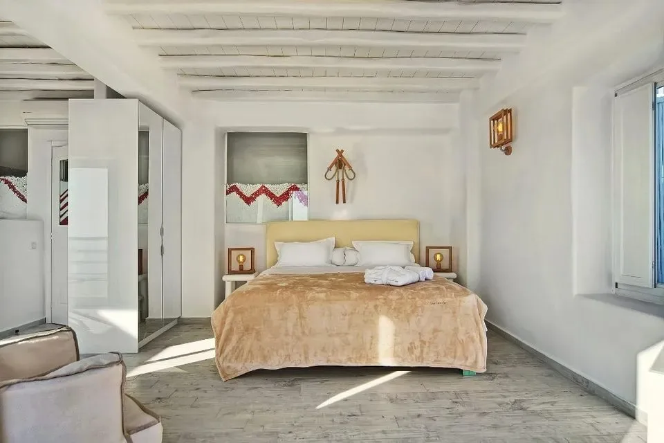 Un dormitorio luminoso con una cama bajo vigas expuestas.