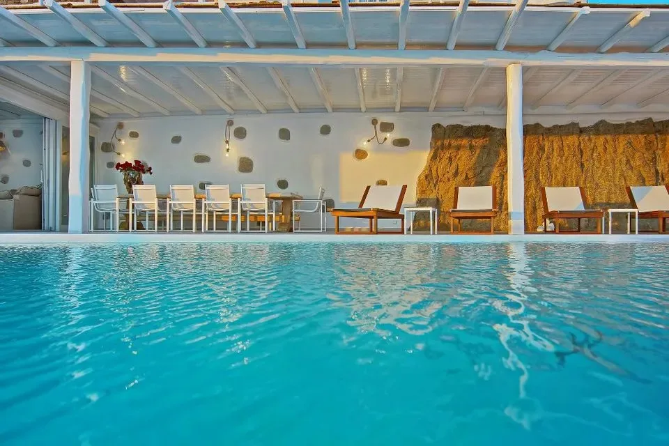 Una piscina cubierta con asientos y muebles de comedor al fondo.