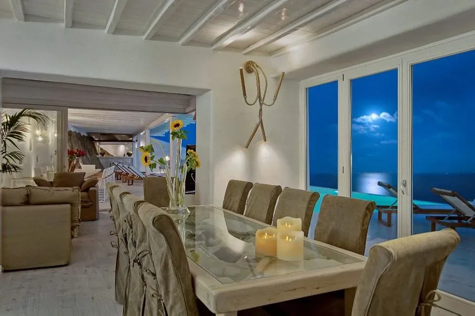 A dining area with a glass table and large windows overlooking the sea.