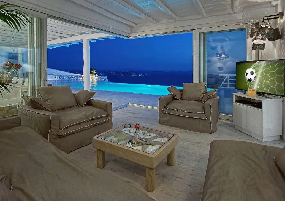 Una sala de estar con asientos y una mesa de centro da a una piscina.