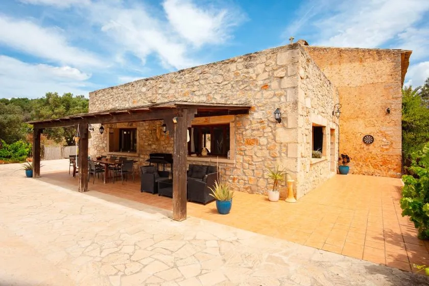 A stone building with a covered outdoor seating area and paved patio.