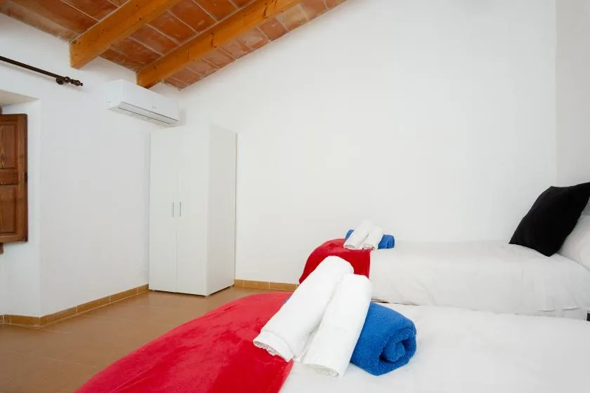 A bright bedroom with white bedding and rolled towels on the bed.