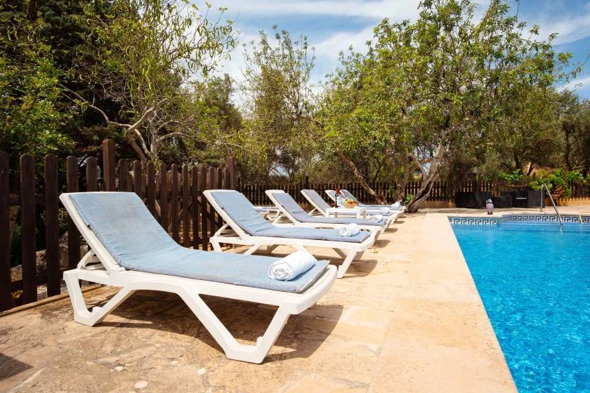 Poolside scene with white loungers arranged along the edge of a swimming pool.