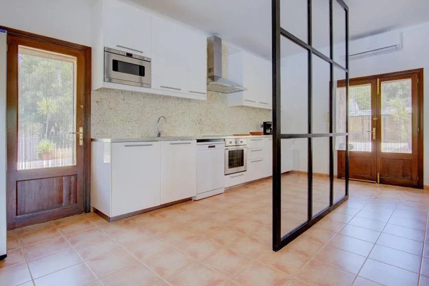 A bright kitchen with white cabinets and a black-framed glass partition.