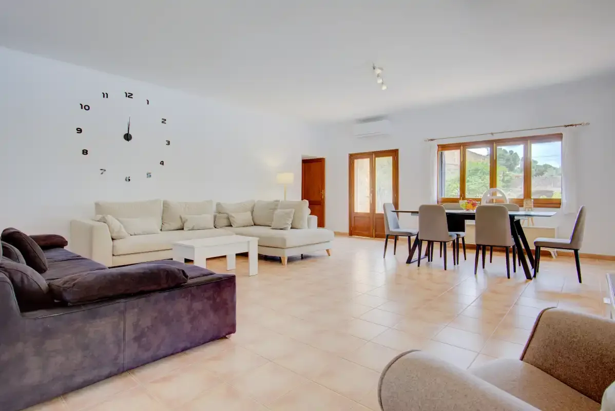 A bright living and dining area with seating, a table, and large windows.