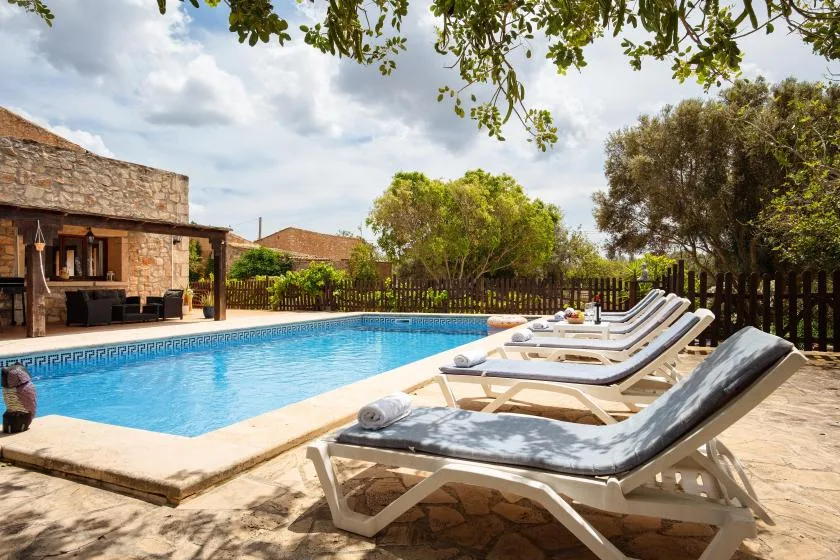 An outdoor swimming pool with lounge seating beside a stone building.