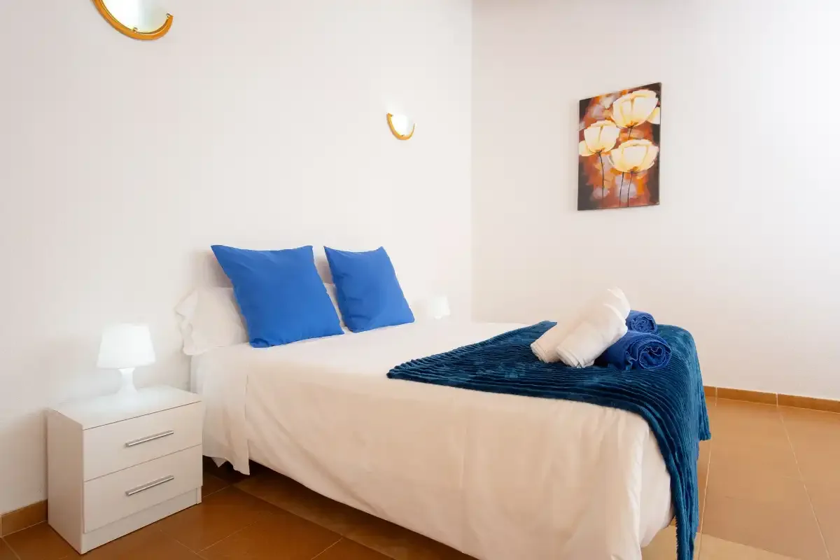 A bedroom with a bed dressed in white and blue bedding.