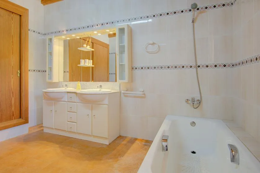A tiled bathroom with a vanity, mirror, and bathtub.
