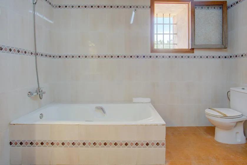 A tiled bathroom with a bathtub, shower fixture, and toilet.
