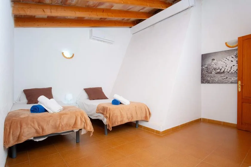 A bedroom with two single beds, folded towels, and exposed wooden ceiling beams.