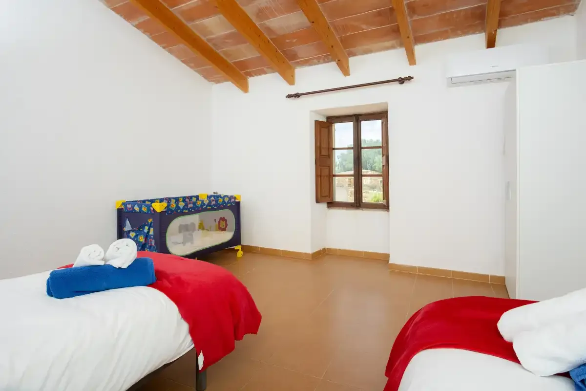A bedroom with two beds and a wooden-beamed ceiling.