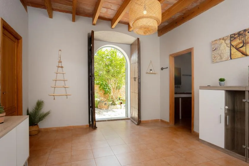 A bright entry hall with an open arched doorway leading to a garden.